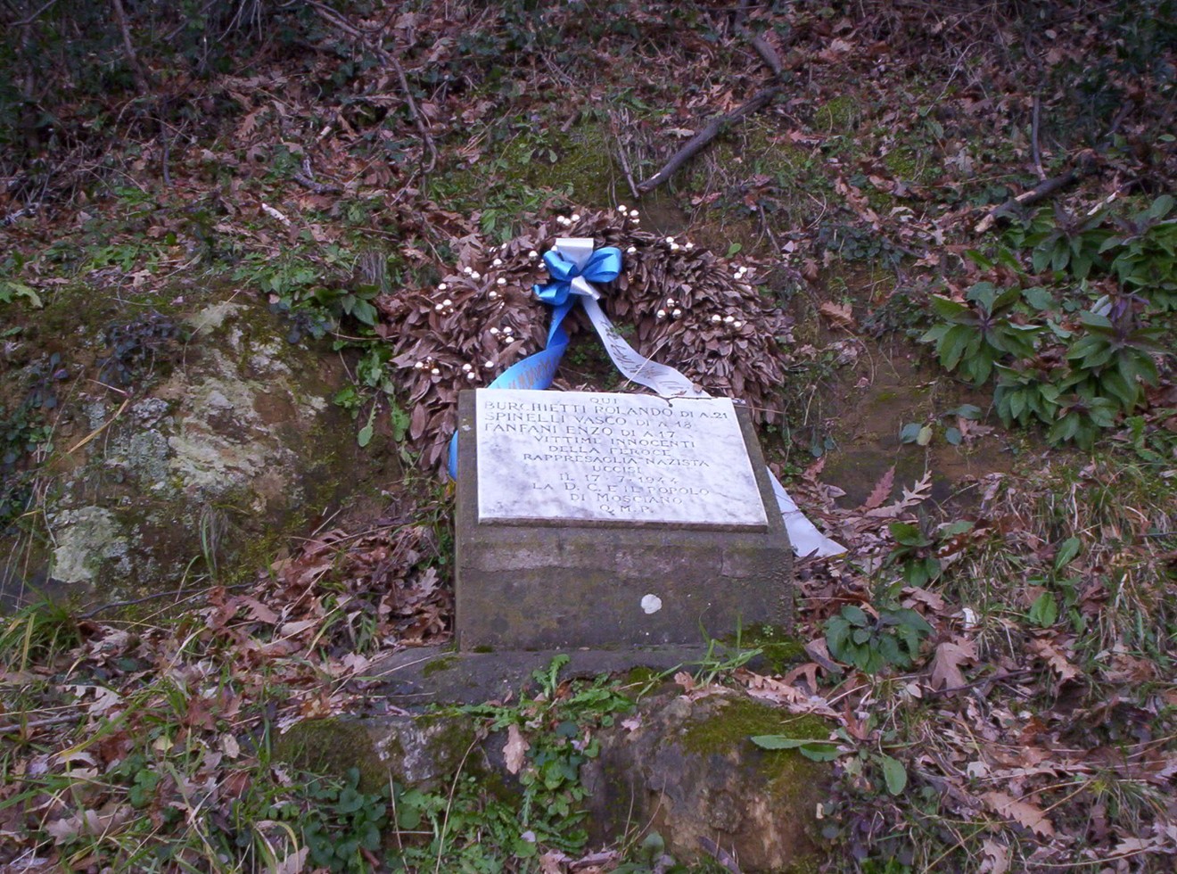 Cippo commemorativo con una corona di fiori, dedicato a Burchietti, Spinelli e Fanfani.