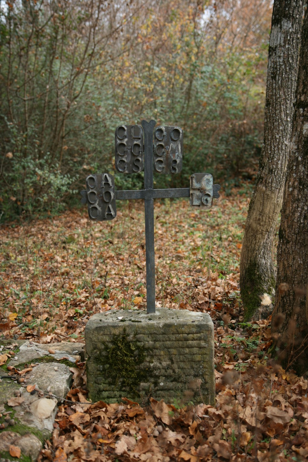 Cippo commemorativo dell'eccidio di Pratale, immerso nella natura e circondato da foglie autunnali.
