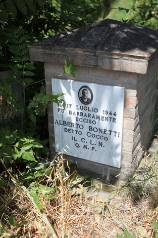 Cippo commemorativo di Alberto Bonetti, ucciso il 17 luglio 1944, circondato da vegetazione.