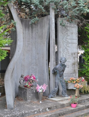 Monumento ai martiri della Resistenza a Pavullo, con statue e dedica ai caduti, circondato da fiori.