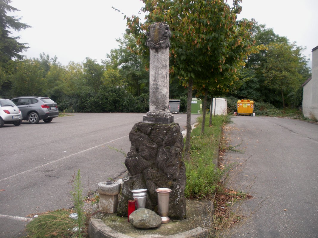Cippo a Bardone, monumento storico circondato da vegetazione e manufatti in un'area di sosta.