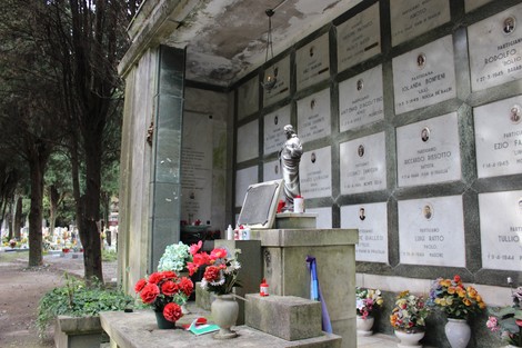 Sacrario dedicato ai caduti per la Liberazione, con fiori e candele su una tomba all'interno di un cimitero.