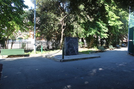 Monumento alla Resistenza in un parco, circondato da alberi e panchine. Ambiente tranquillo e suggestivo.