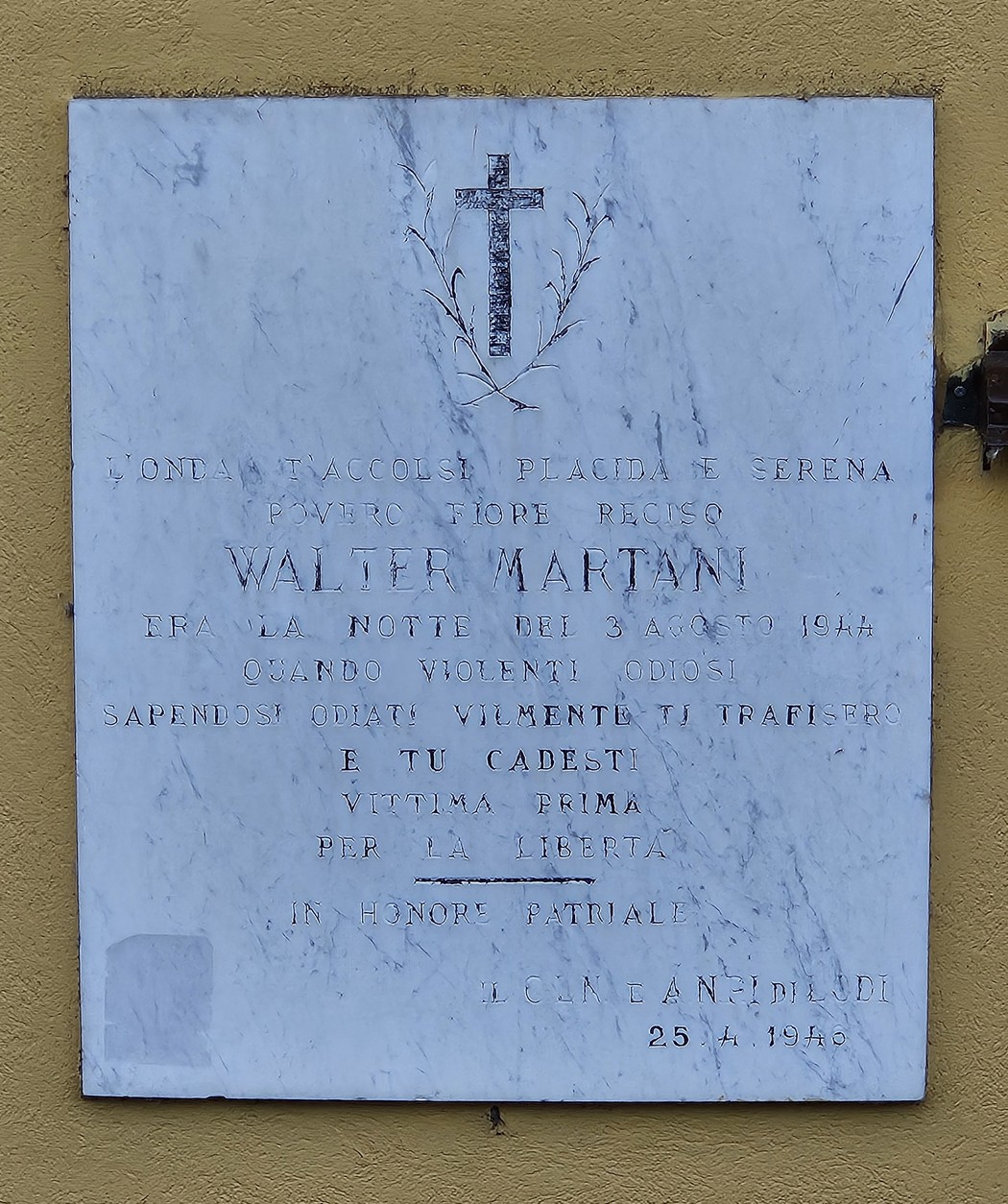 Lapide commemorativa di Walter Martani, con una croce e iscrizioni in onore della sua memoria.