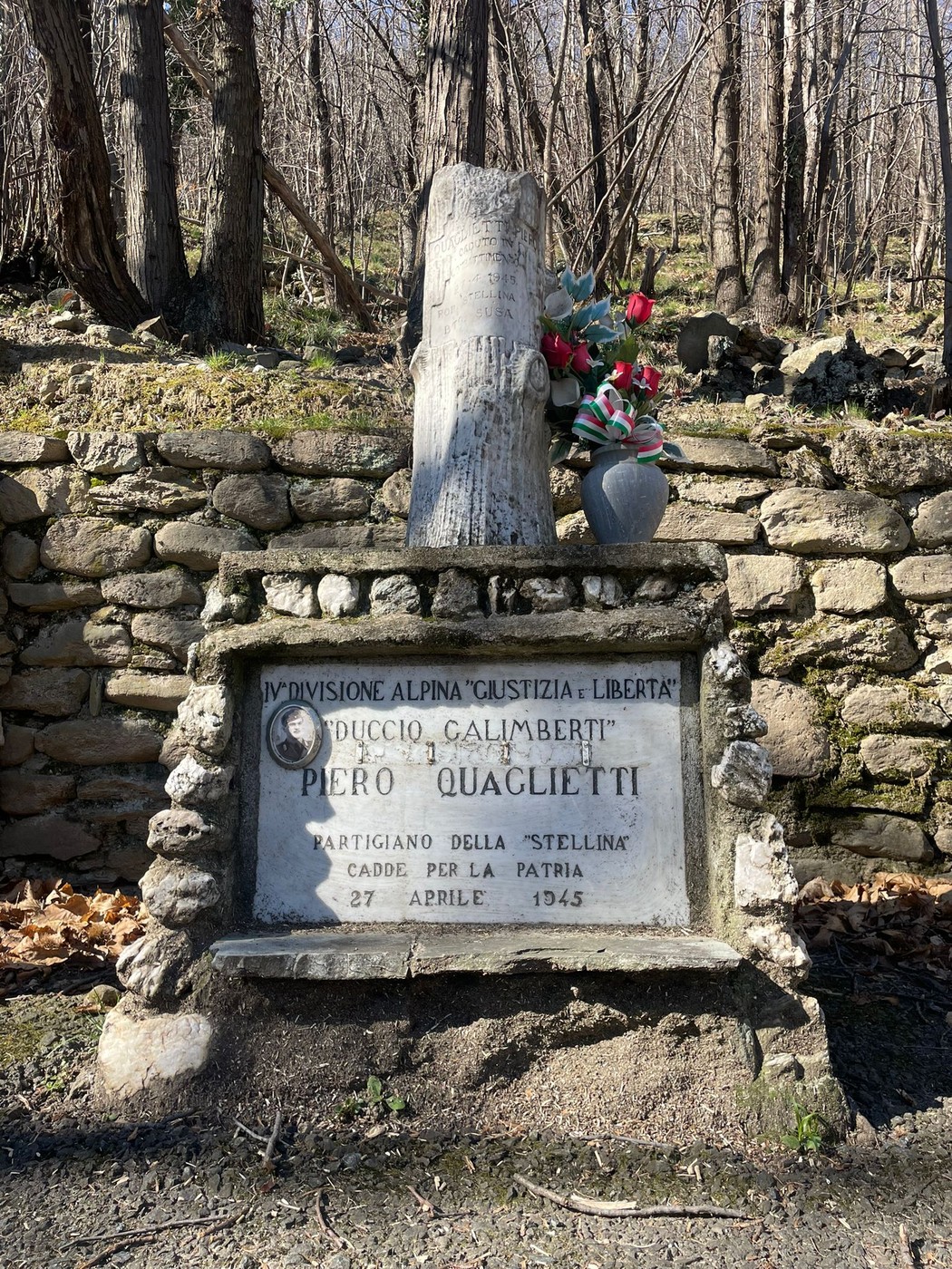 Cippo commemorativo dedicato a Piero Quaglietti, partigiano, situato in un bosco.