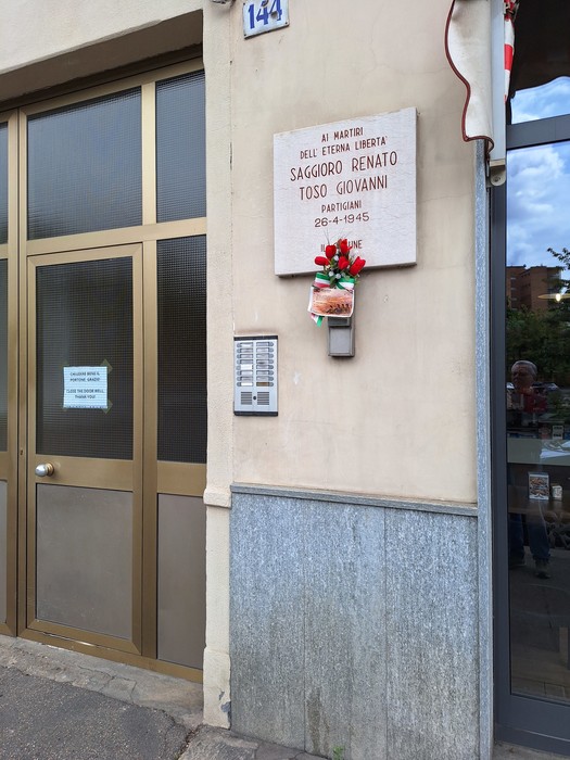 Lapide commemorativa in onore dei martiri di Saggioro e Toso, affissa su una parete esterna.