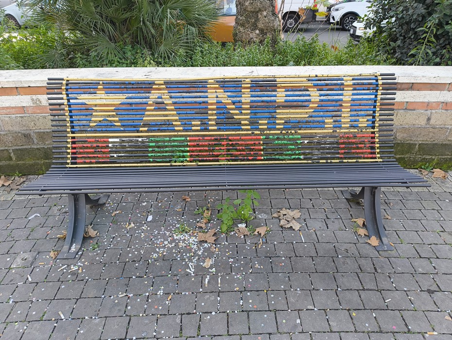 Panchina decorata con il simbolo dell'ANPI, rappresentando i valori della Resistenza. Elementi di colore vivace.
