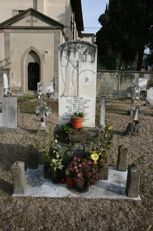 Sepolcro dei 17 partigiani, monumento commemorativo con fiori e piante in un cimitero.