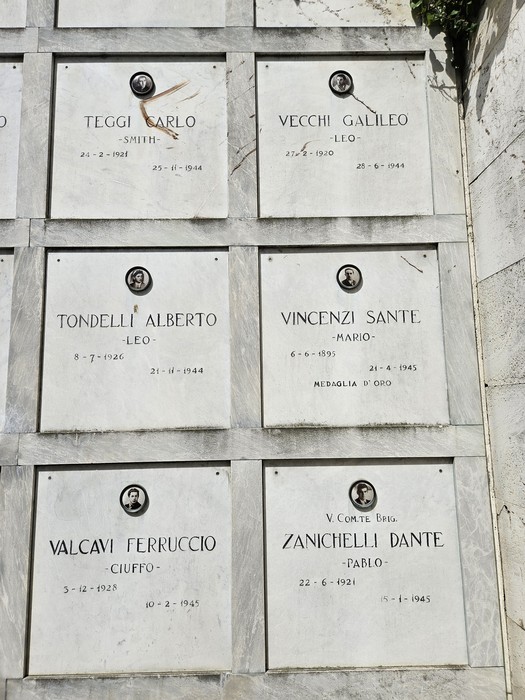 Monumento ai Caduti Partigiani con lapidi commemorative e fotografie di eroi della Resistenza.