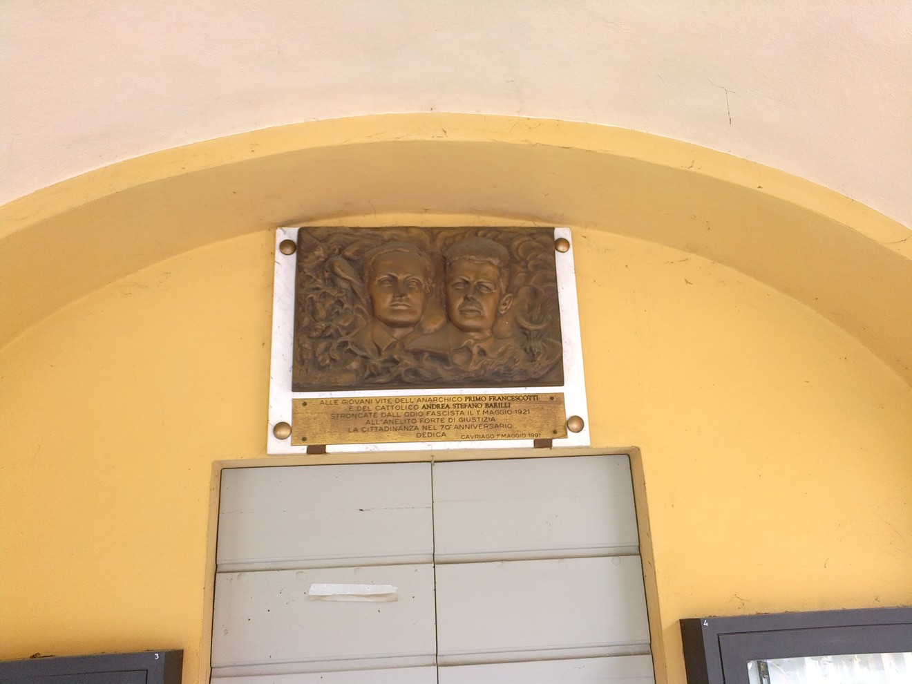 Targa commemorativa dedicata a Francescotti e Barilli, incastonata in una parete gialla.