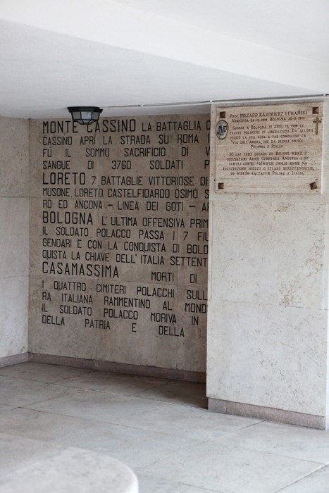 Cimitero di guerra polacco con monumenti commemorativi e iscrizioni storiche sul conflitto.