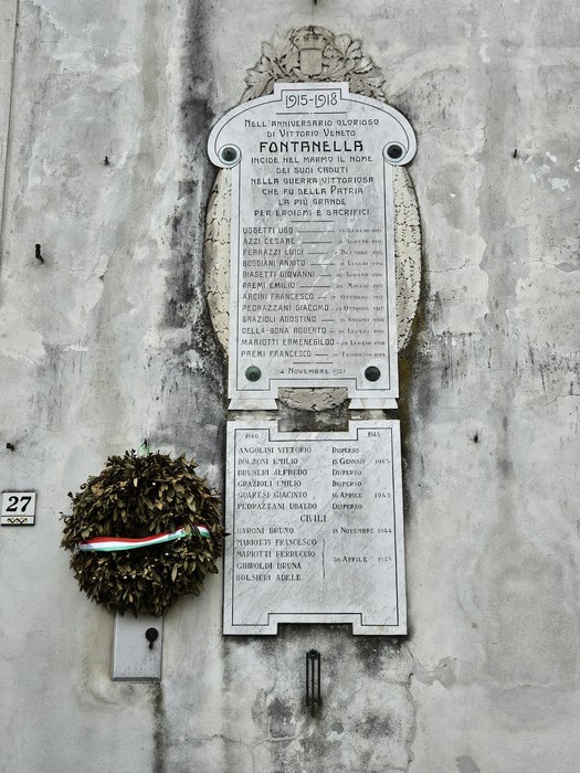 Lapidi commemorative ai caduti di Fontanella Grazioli, con corone di fiori e iscrizioni storiche.