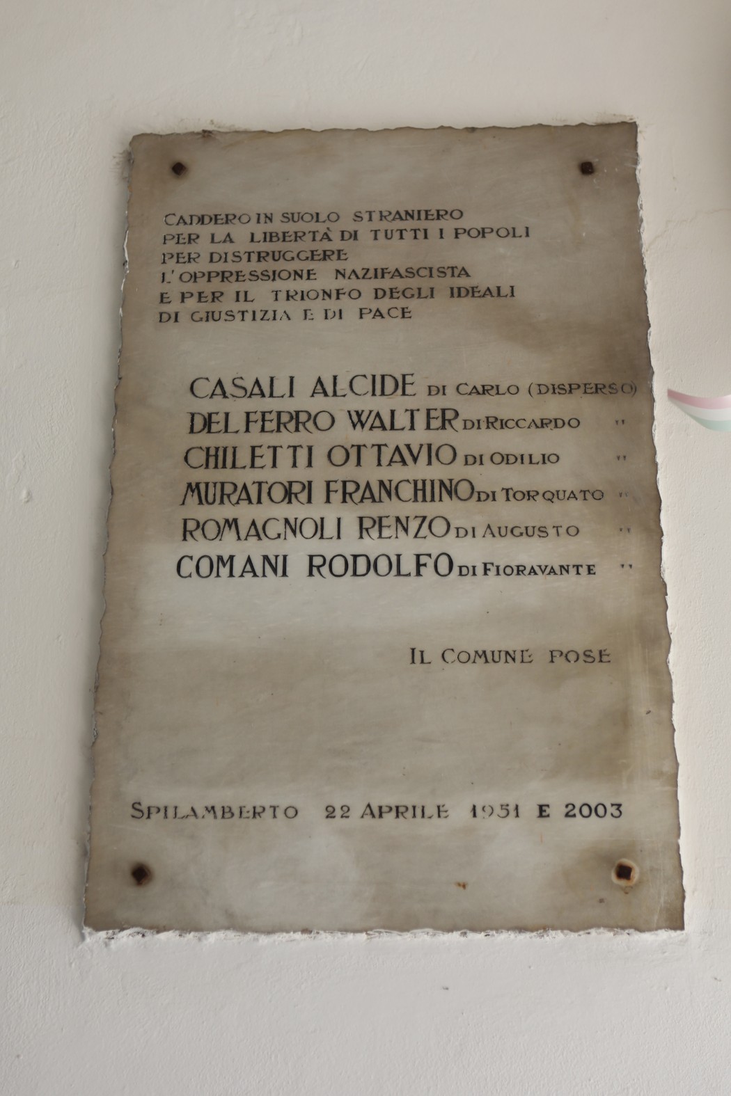 Lapide commemorativa dedicata ai partigiani italiani all'estero, con nomi e date incisi.