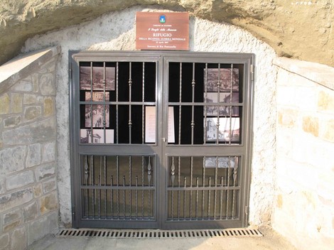 Entrata del Rifugio di guerra di Pianoro, con cancello e pareti in pietra, che conserva la memoria storica.