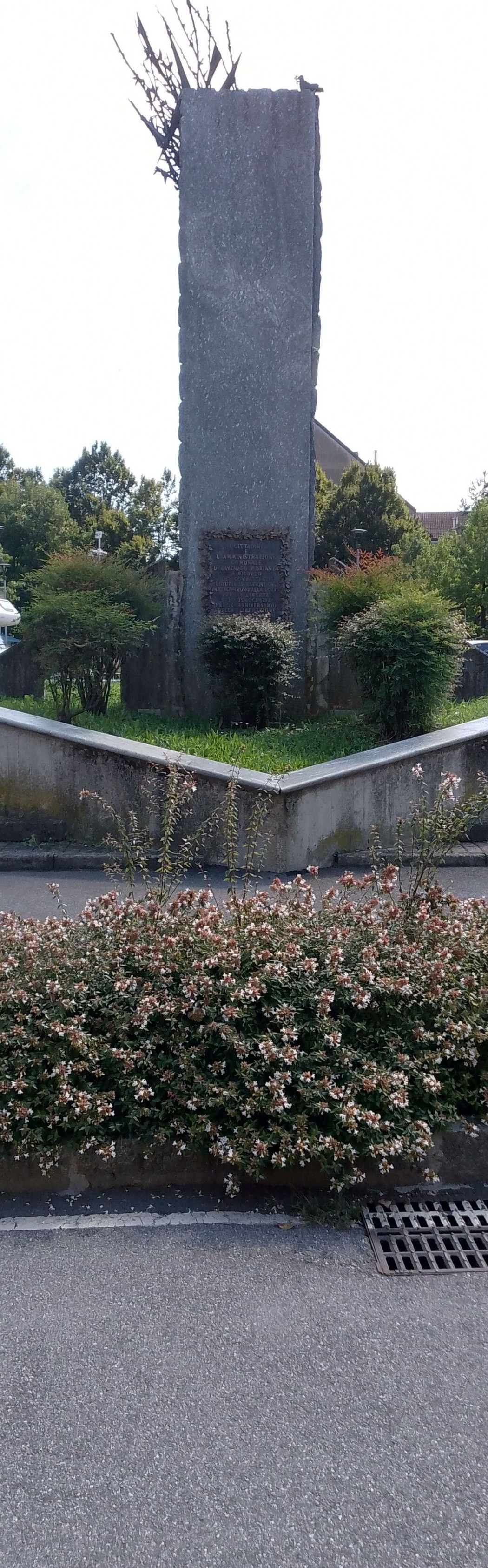 Monumento ai combattenti per la Libertà, circondato da verdure e aiuole fiorite.