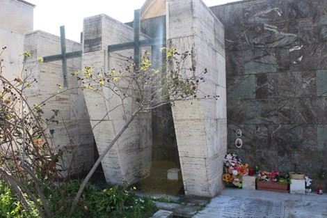 Monumento ai caduti di Palmaro, struttura moderna con elementi verticali e decorazioni floreali circostanti.
