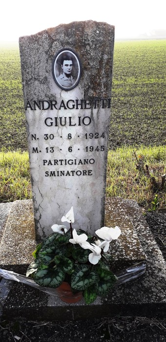 Cippo commemorativo di Giulio Andraghetti, partigiano scomparso nel 1945, immerso nel paesaggio rurale.