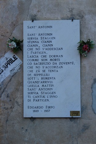 Lapide commemorativa di Sant'Antonin, decorata con fiori e apposta su una parete di pietra.