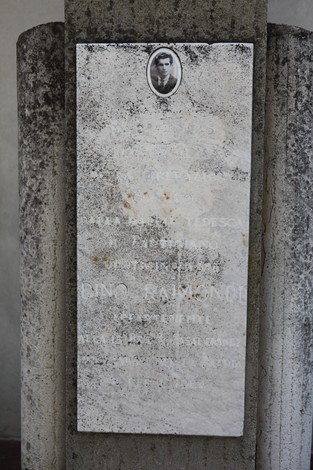 Cippo commemorativo con iscrizioni e fotografia di un soldato in memoria di Dino Raimondi.