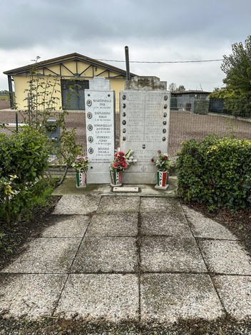 Monumento ai caduti partigiani di Cortile, con iscrizioni e fiori commemorativi.