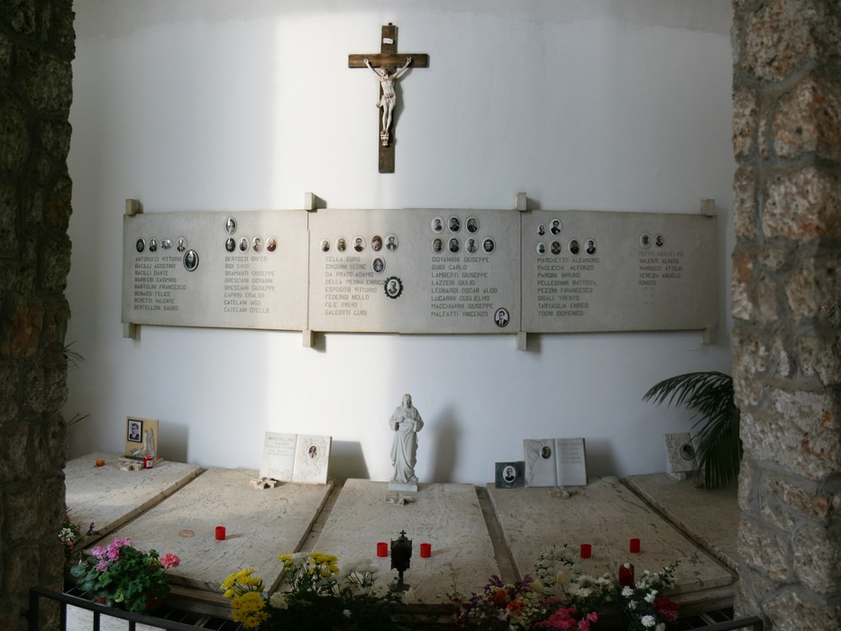 Sacrario dei martiri di San Terenzo: luogo di memoria con lapidi, croce e fiori in onore dei defunti.