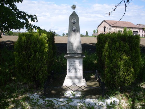 Monumento commemorativo a Ferretti e Severi, circondato da vegetazione in un'area rurale.