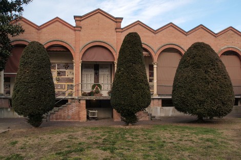 Sacrario dei caduti di Cortile, con alberi ornamentali e struttura architettonica in mattoni.