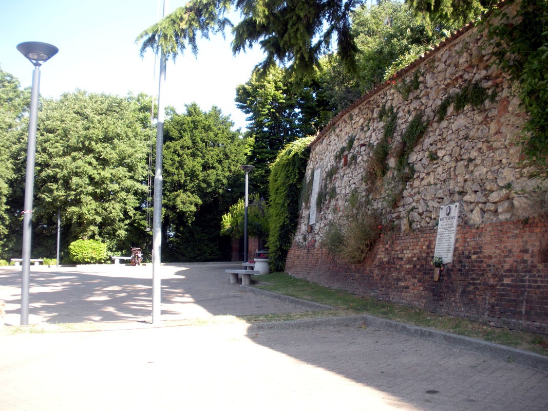 Lapide commemorativa dedicata a Moretti, situata in un parco tranquillo tra alberi e dettagli storici.