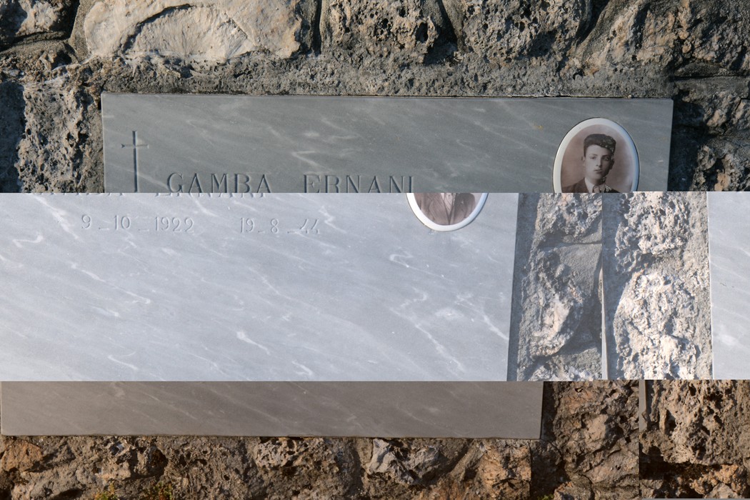 Dettagli del monumento commemorativo nell'Ossario di Sant'Anna di Stazzema, con lastre di marmo e fotografie.