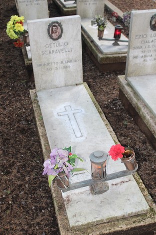Tombe dei caduti per la Libertà, con fiori freschi e candele, in un cimitero commemorativo.