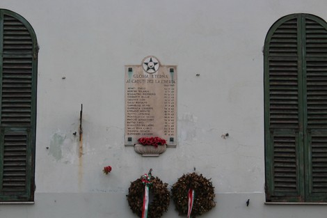 Lapide commemorativa ai caduti per la Libertà di Bolzaneto, con omaggi floreali e simboli patriottici.