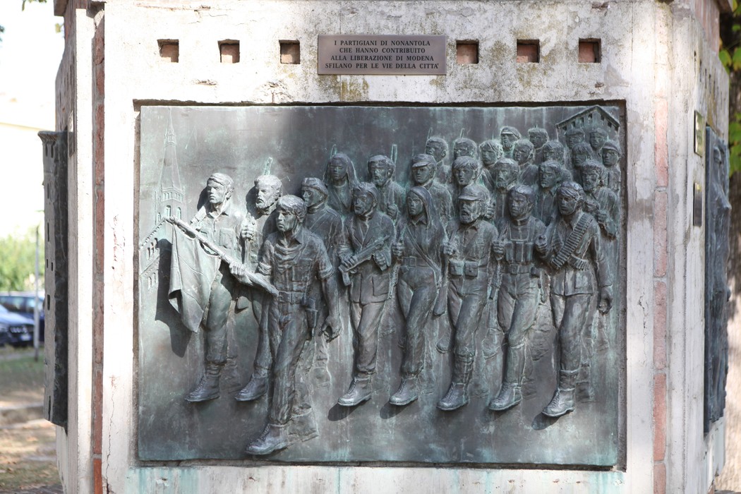 Monumento alla Resistenza con bassorilievo che ritrae partigiani in marcia, simbolo di lotta e libertà.