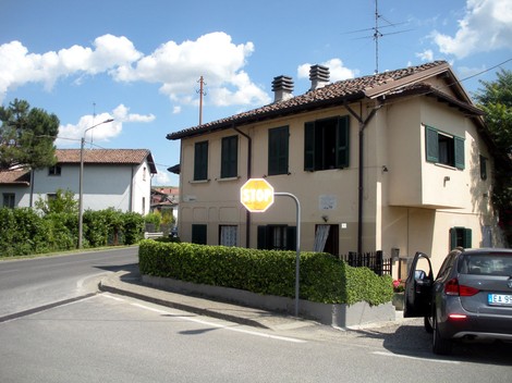 Lapide a Pontiroli, con vista su un edificio e segnale stradale, circondato da verde e cielo sereno.