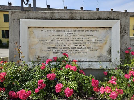 Monumento alla Brigata Balladore con una base decorata e fiori rosa nei pressi, simboleggia il ricordo e il sacrificio.