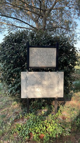 Lapidi commemorative dedicate ai partigiani delle valli ravennati tra vegetazione.