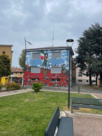 Murale commemorativo delle staffette partigiane, con fiori rossi e simboli della resistenza italiana.