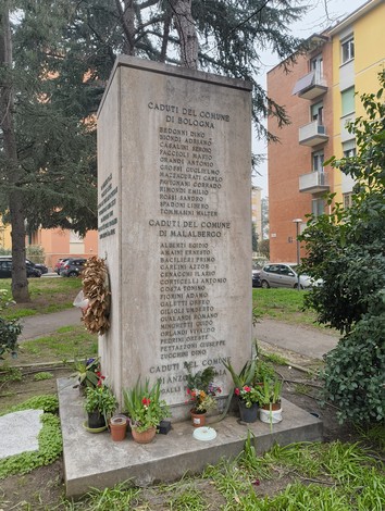 Monumento ai partigiani uccisi a San Ruffillo, con iscrizioni e fiori ai piedi. Rappresenta la memoria storica.