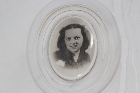 Immagine di un ritratto incorniciato di una giovane donna con capelli ricci, espressione sorridente e sfondo chiaro.