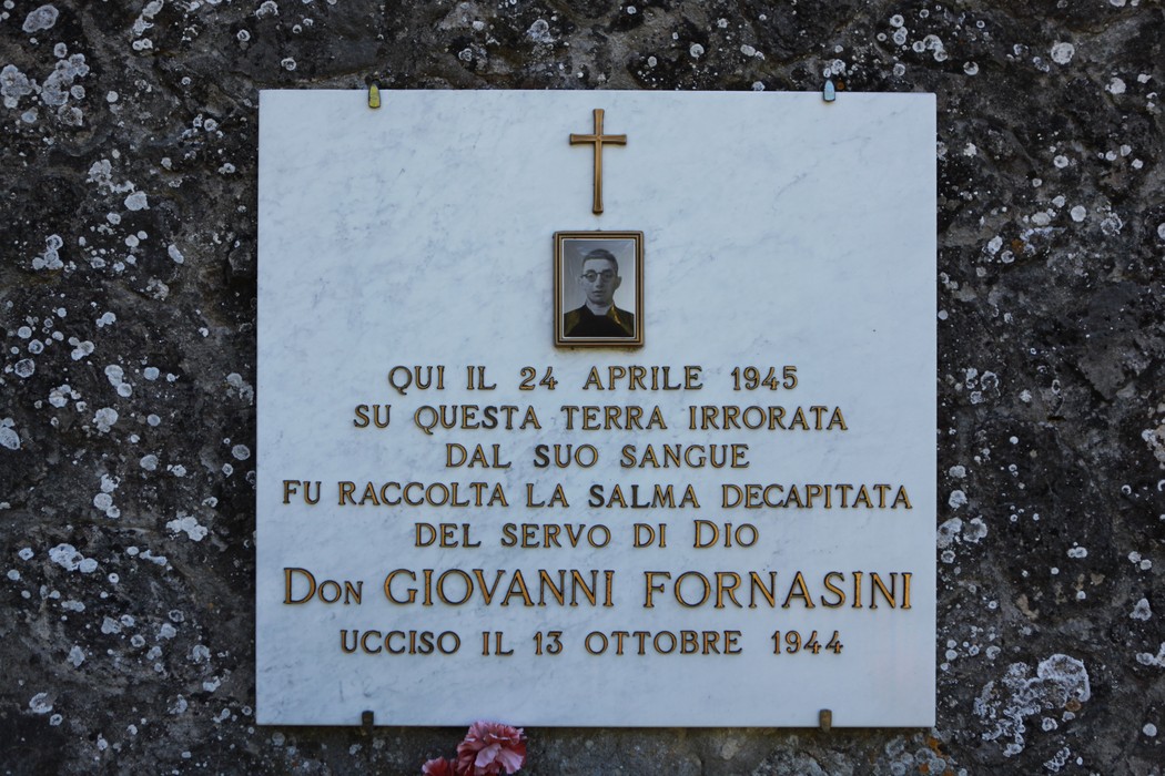 Lapide commemorativa dedicata a Don Giovanni Fornasini, ucciso nel 1944, situata in un luogo significativo.