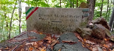 Lapide commemorativa di Braghin e Acquadro, visibile tra gli alberi in un ambiente boschivo.