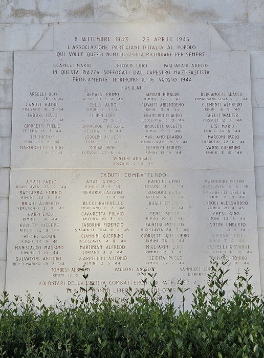 Lapide commemorativa dedicata ai caduti per la libertà, con nomi di martiri e combattenti. Ambiente solenne e riflessivo.