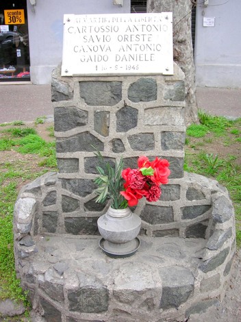 Cippo commemorativo in pietra con fiori, dedicato a Cartossio, Savio, Canova e Gaido. Memoriale di libertà.