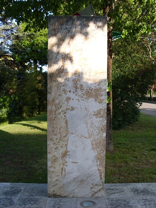 Monumento a Borghi, una stele in pietra circondata da verde, simbolo di memoria e storia.