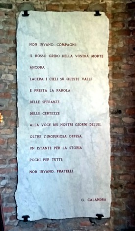 Il sacrario commemorativo con iscrizioni su una parete di pietra, simbolo di memoria e devozione.