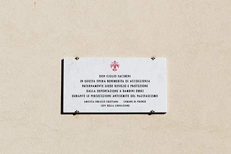 Lapide commemorativa di Don Facibeni, riconosciuto per la sua opera di accoglienza e protezione durante la guerra.