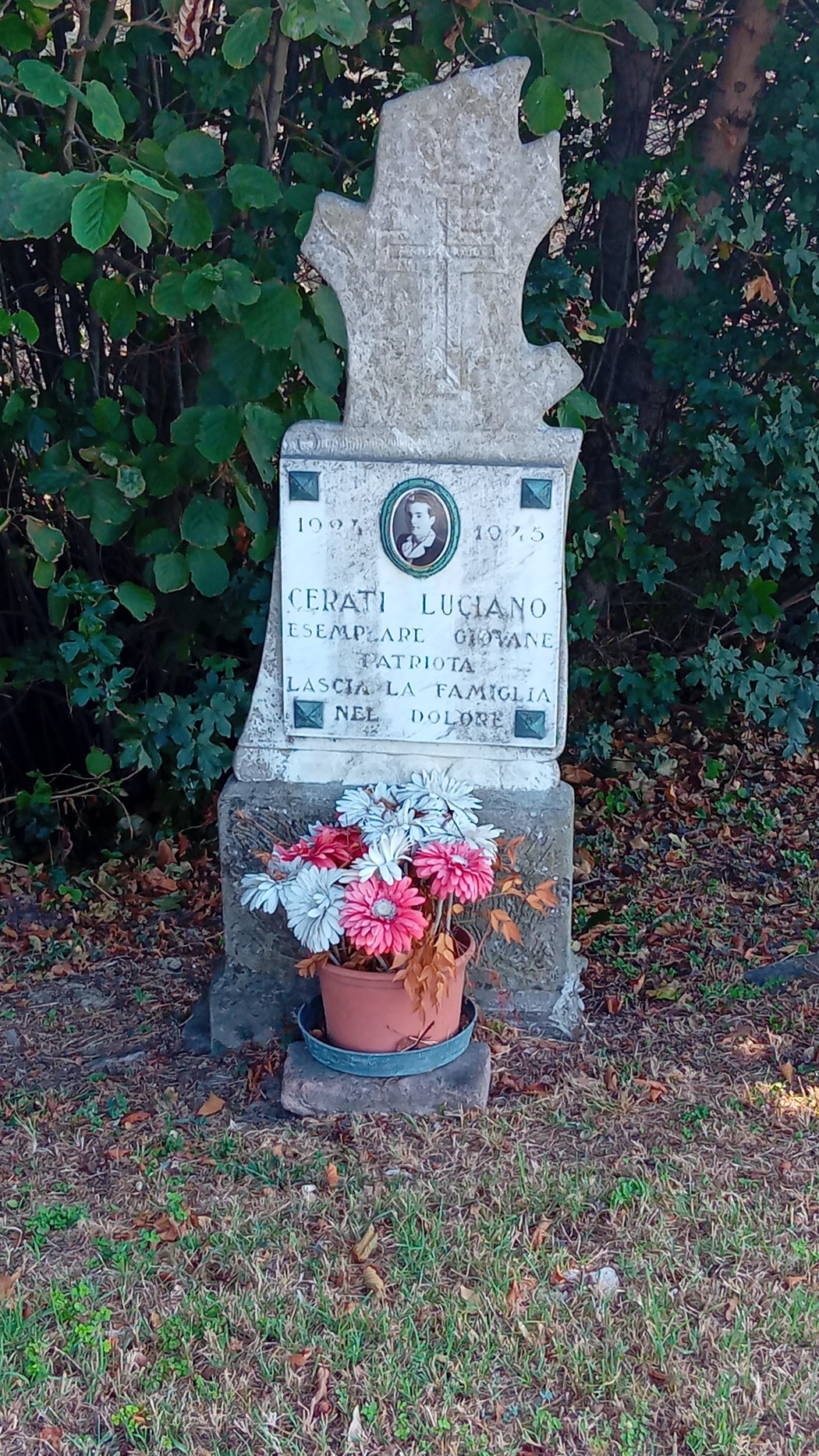 Cippo commemorativo dedicato a Luciano Cerati, con decorazioni floreali.
