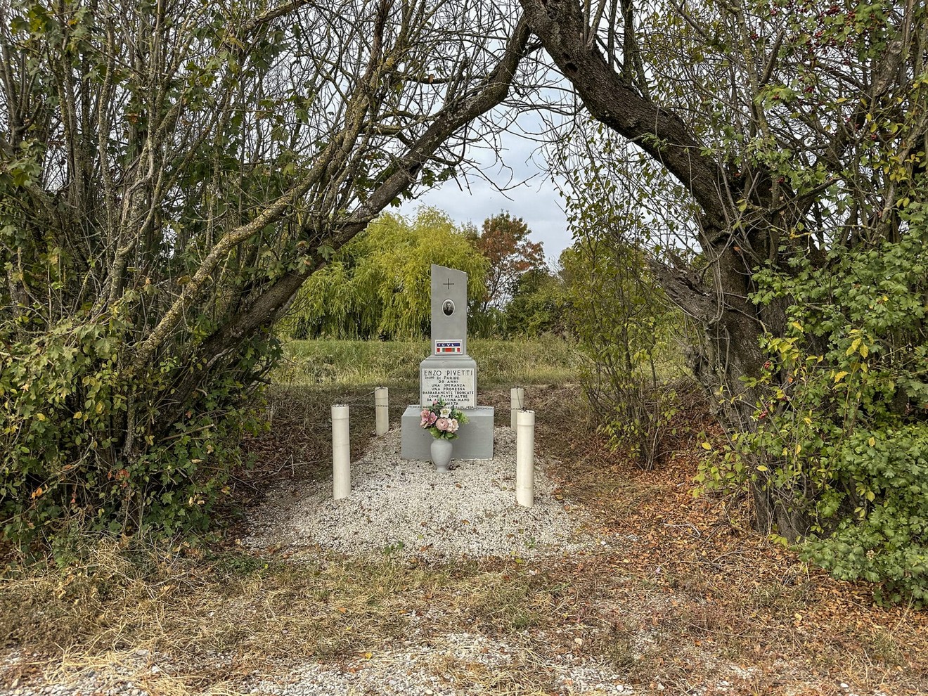 Cippo a Pivetti circondato da natura, con fiori e monumento in un'area tranquilla e silenziosa.