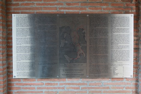Cimitero di guerra del Commonwealth con lapidi e simboli commemorativi immersi nel verde.