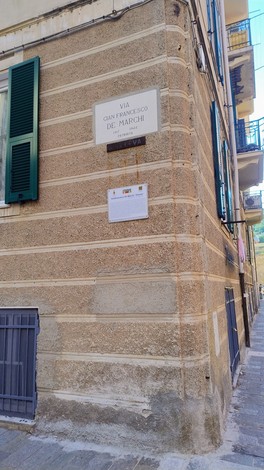 Targa stradale che indica "Via Giovanni Francesco De Marchi" su un muro angolare di un edificio.