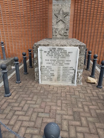Monumento ai Martiri del Cabina con base in pietra e colonna, circondato da catene e paletti.